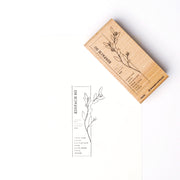 Ein Alexandra Renke Holzstempel mit Blumenmotiv liegt neben seinem Druck auf weißem Papier, beide zeigen die gleiche Blume und den gleichen deutschen Text - ideal für Stempelgummi oder fantasievolle Papierprojekte.