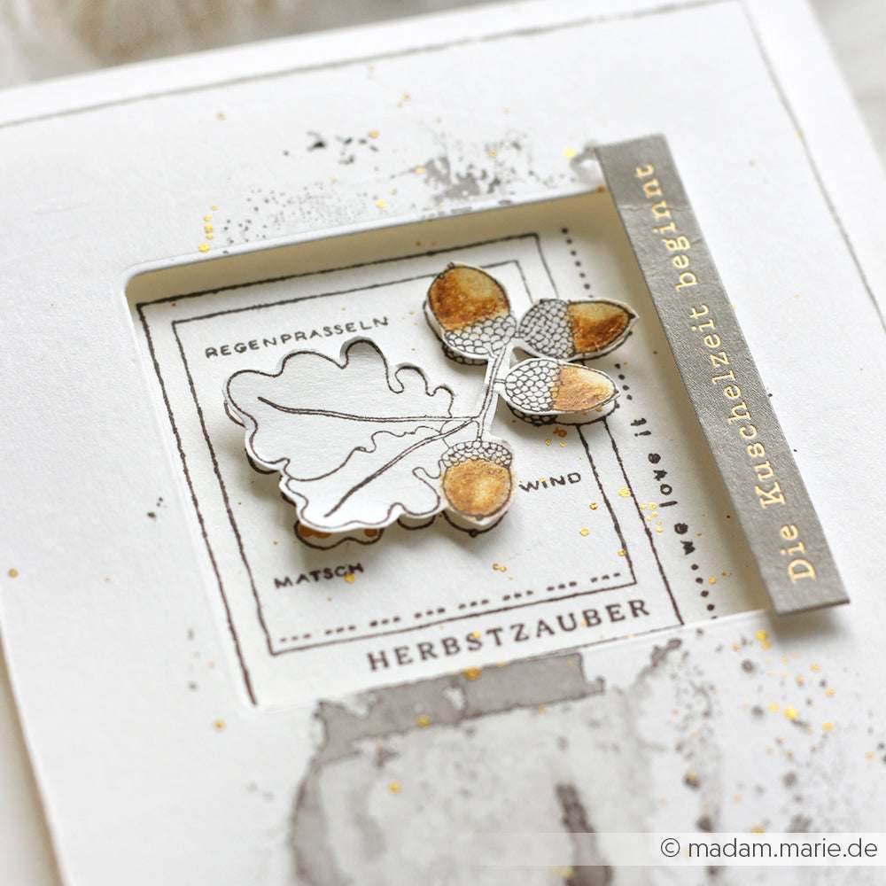 Handgefertigte Herbstkarte von Alexandra Renke mit Blattmotiv, deutschem Text und goldenen Akzenten auf Weiß - perfekt für Papierprojekte oder um Eicheln Herbstzauber in Ihre saisonalen Grüße einzubauen.