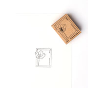 Ein Alexandra Renke Krokus Blumenpost Holzstempel mit einem zarten Blumenmotiv ruht neben seinem gestempelten Bild auf weißem Papier und hebt die scharfen Details seines Stempelgummis hervor.