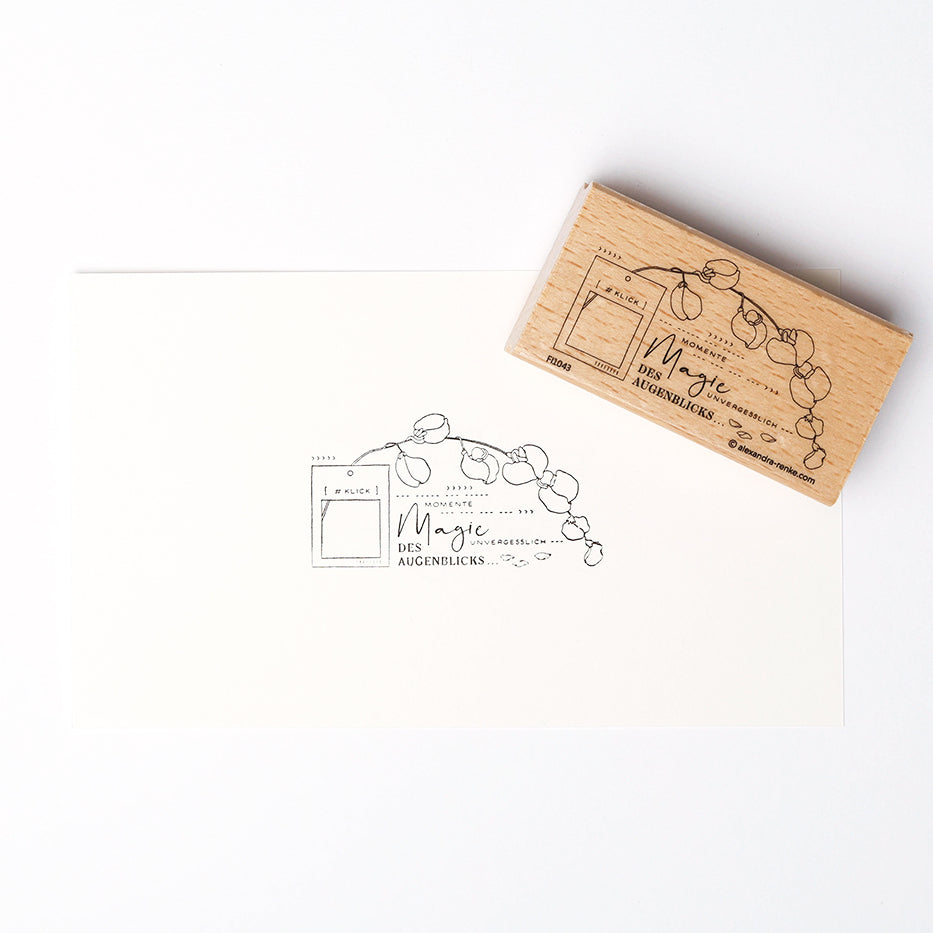 Ein Holzstempel von Alexandra Renke mit floralem Design und deutschem Text schafft einzigartige Drucke auf weißem Papier - ideal für besondere Papierprojekte.