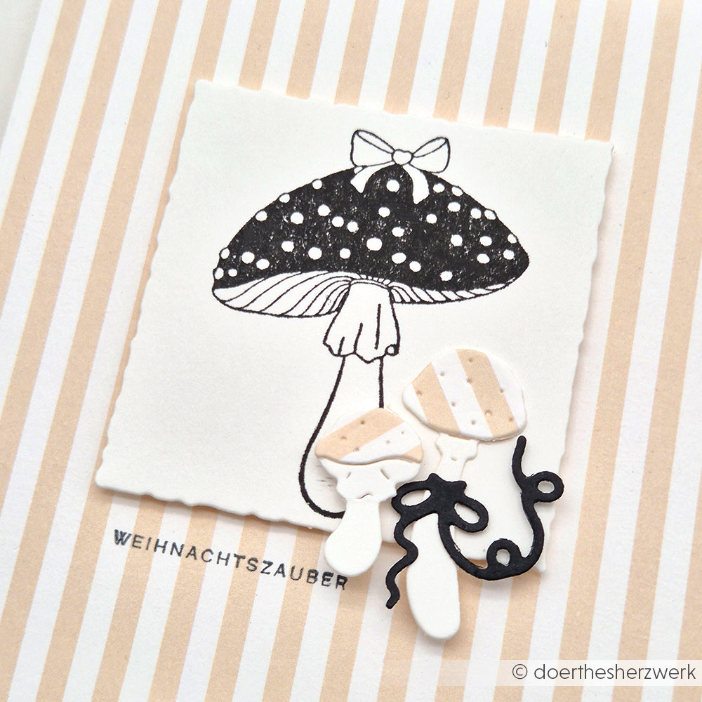 Schwarz-weiße Pilzzeichnung mit zwei kleinen 3D-Papierpilzen auf gestreiftem Hintergrund, mit dem Fliegenpilz Stempel von Alexandra Renke für charmante Stempeldesigns.