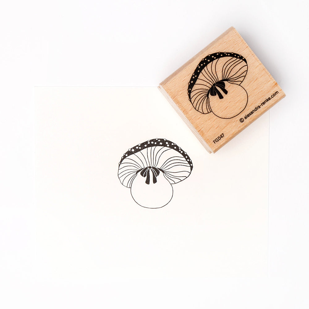 Ein hochwertiger Alexandra Renke Holzstempel erzeugt einen schwarzen Pilzaufdruck auf weißem Papier.