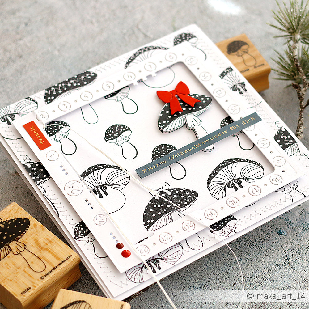 Handgefertigte Weihnachtskarte von Alexandra Renke mit schwarz-weißen Pilzen, einer roten Schleife und deutschem Text auf hellem Hintergrund - ideal für Papierprojekte oder mit Ihrem Lieblingsholzstempel.
