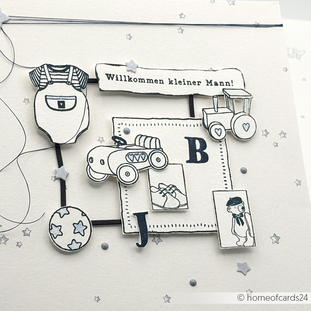 Handgefertigte Karte von Alexandra Renke mit Artikeln für einen kleinen Jungen, deutschem Text "Willkommen kleiner Mann!", Schwarz-Weiß-Illustrationen und charmanten Holzstempel-Akzenten, die einen neugierigen Bären zeigen.