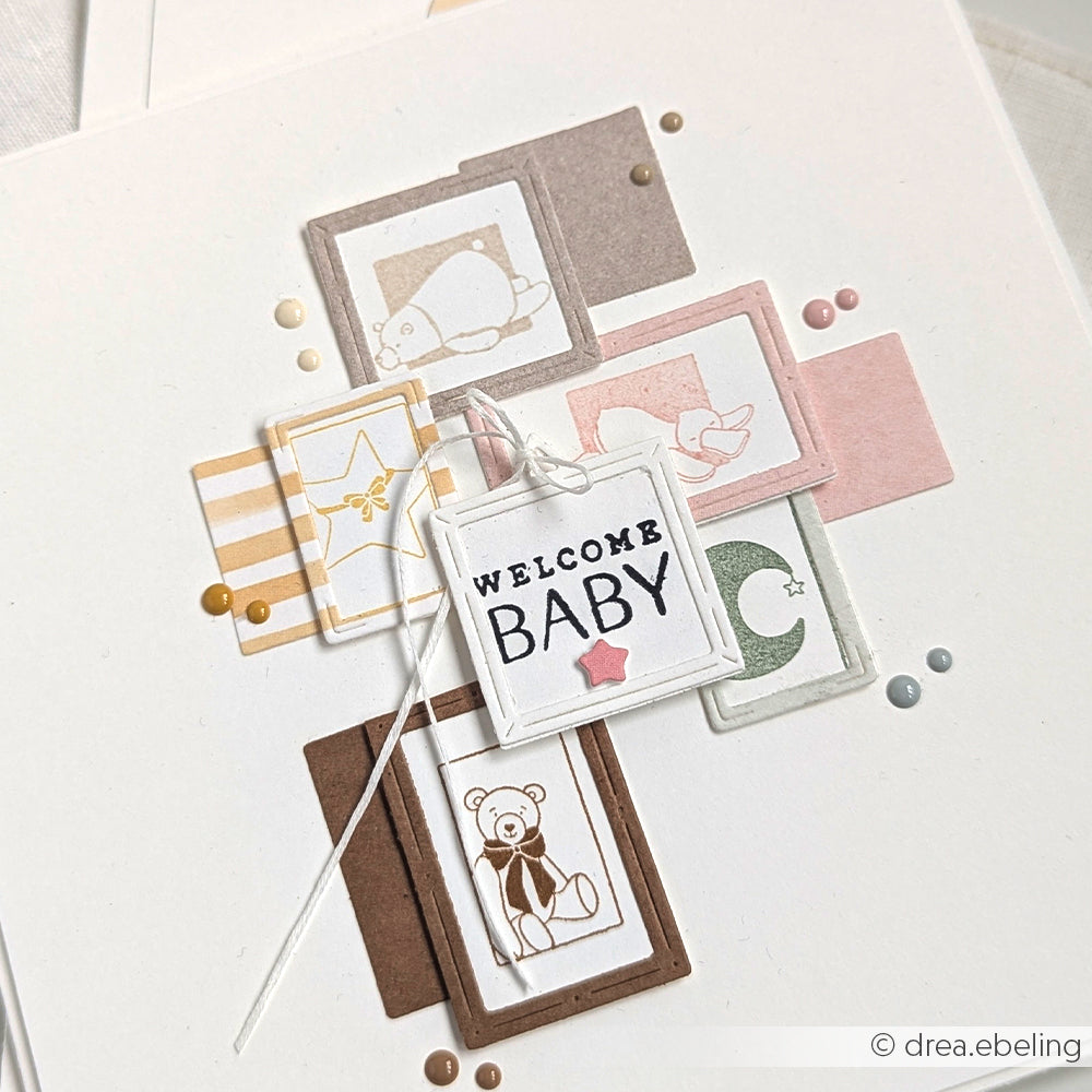 Eine Welcome Baby-Karte von Alexandra Renke mit pastellfarbenen Blöcken, Baby-Symbolen und farbigen Punkten auf Weiß - ideal für Papierprojekte oder in Kombination mit Ihren Lieblings-Holzstempel-Motiven.