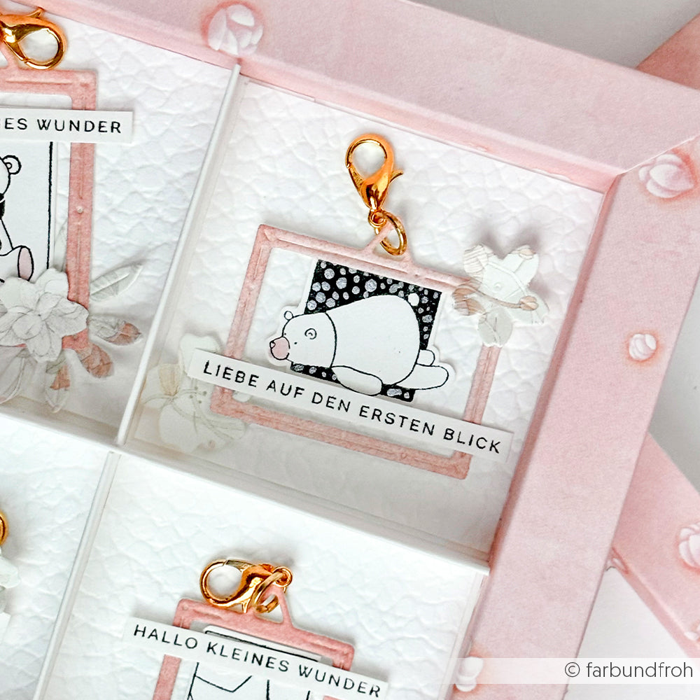 Rosa gerahmter Schlüsselanhänger mit einer weißen Bärenillustration und dem Spruch "LIEBE AUF DEN ERSTEN BLICK" - ein charmantes Accessoire von Alexandra Renke, ideal für Fans von niedlichen, handwerklich inspirierten Designs.