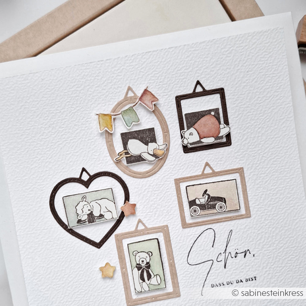 Illustrierte Karte von Alexandra Renke mit gerahmten Spielzeug-, Tier- und Sternenzeichnungen auf strukturiertem weißem Papier, mit dem bezaubernden Schlafendes Entchen, das mit Holzstempeln und zarten Prägetechniken hergestellt wurde.