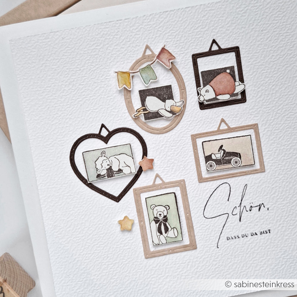 Gerahmte Skizzen von Spielzeugen und Tieren von Alexandra Renke, die Stempelmotive wie Holzstempel und Stempel Schlafendes Lämmchen zeigen, dekorativ angeordnet auf strukturiertem weißem Papier mit Sternen und deutschem Text.