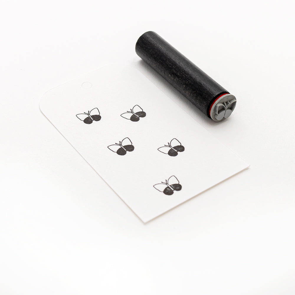 Alexandra Renke Akzent-Stempel Mini Schmetterling in schwarz steht neben einer weißen Karte mit fünf schwarzen Schmetterlingsstempeln, alle auf weißem Hintergrund.