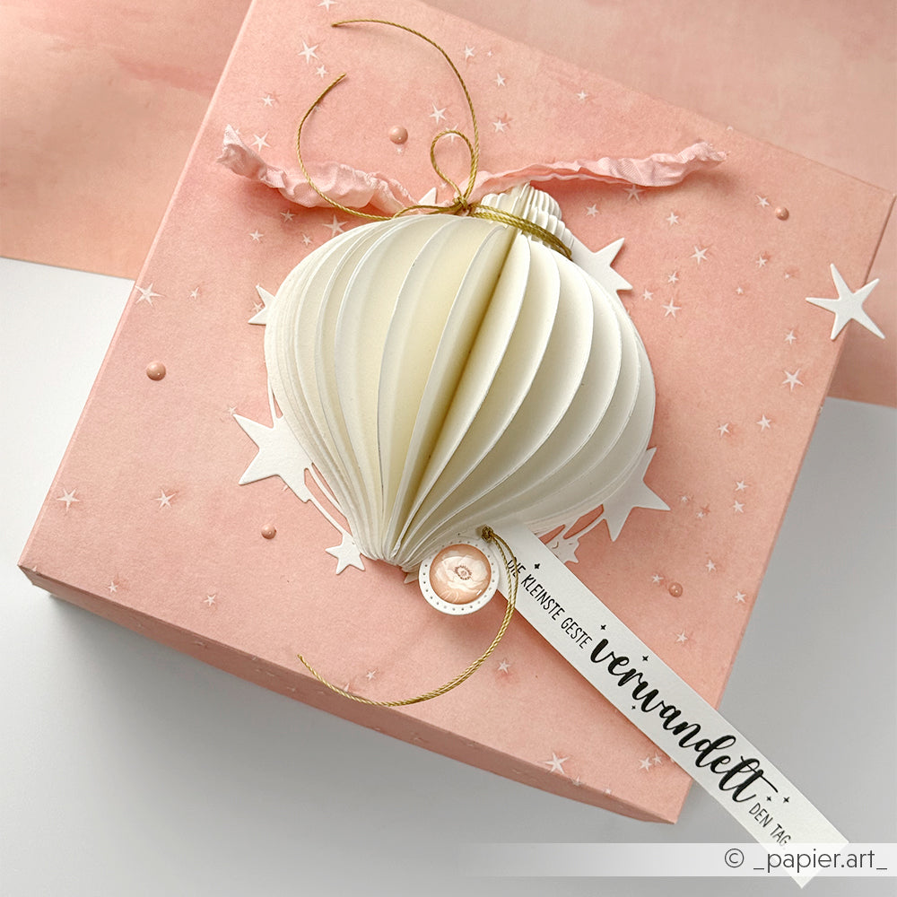 Rosa Geschenkbox von Alexandra Renke mit einem 3D-Papierornament, goldener Schnur, weißen Sternen und einem Anhänger mit deutschem Text - ideal für die Präsentation von detailreichen Motiven mit Holzstempel oder Stempelkissen.