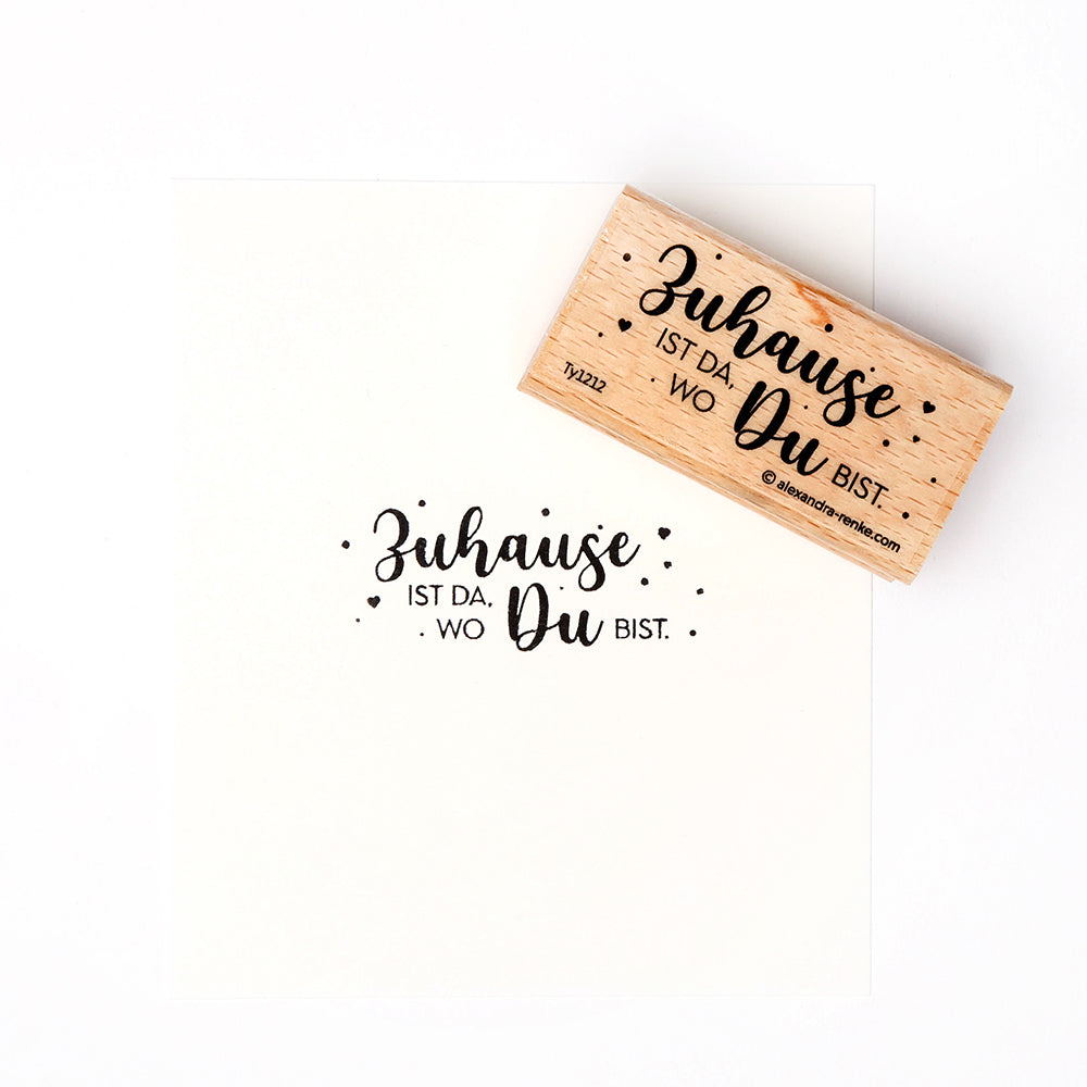Ein Holzstempel von Alexandra Renke mit dem deutschen Spruch "Zuhause ist da, wo Du bist." - perfekt für kreative Papierprojekte und liebevolle Gestaltungen.