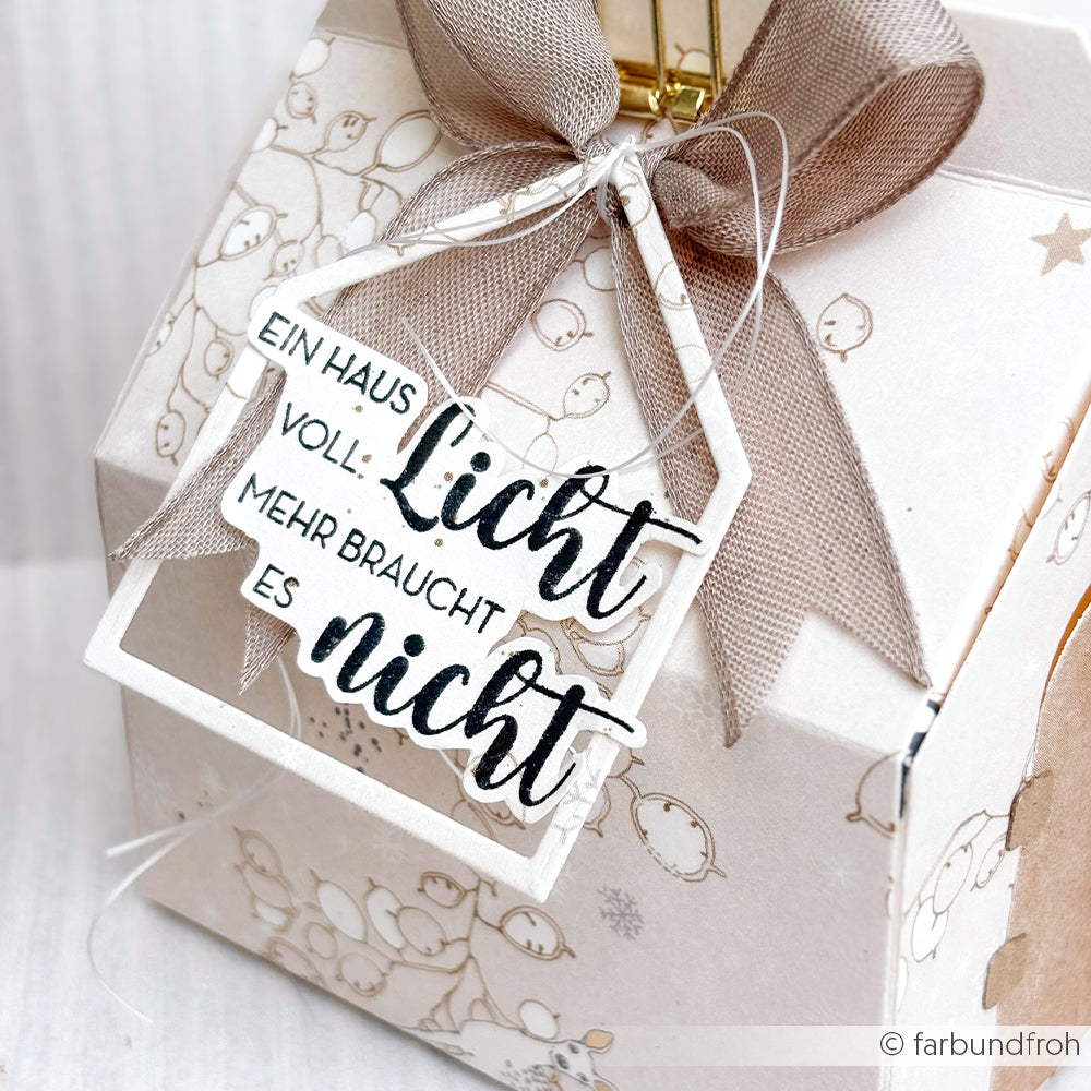 Geschenkbox von Alexandra Renke mit beigem Band und Anhänger: "Ein Haus voll Licht, mehr braucht es nicht." Verziert mit einem hochwertigen Holzstempel mit aufwändigem Muster.