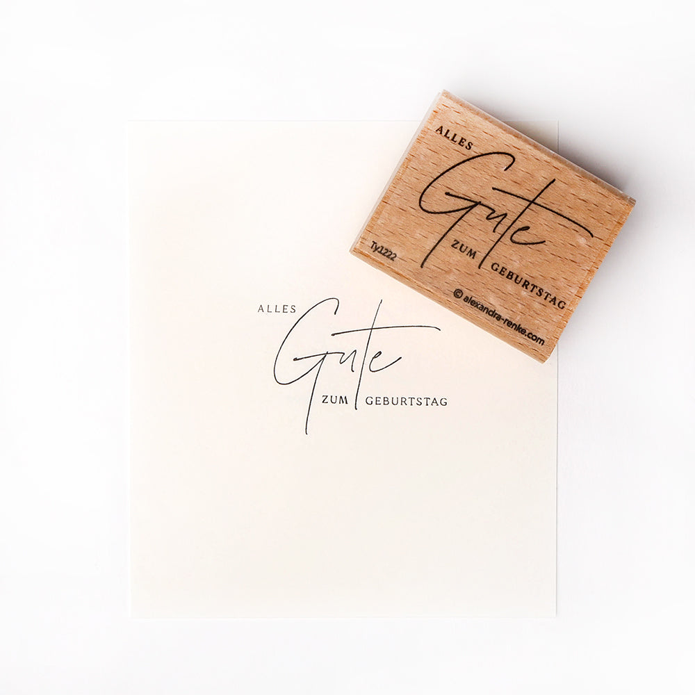 Ein Alexandra Renke Holzstempel und gestempeltes Papier mit der Botschaft "Alles Gute zum Geburtstag".