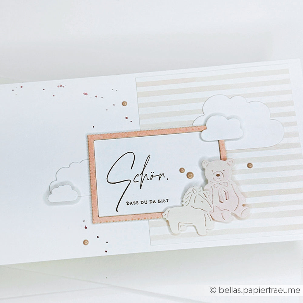 Grußkarte von Alexandra Renke mit pastellfarbenen Wolken, einem Teddybär und dem Text "Schön, dass du da bist" auf Streifen - ideal für Papierprojekte oder in Kombination mit Ihren Lieblingsholzstempeln und Stempelkissen.