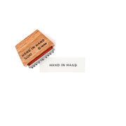 Ein Holzstempel von Alexandra Renke mit der Aufschrift HAND IN HAND hinterlässt seinen Stempelgummi-Abdruck auf weißem Papier - ideal für kreative Papierprojekte.