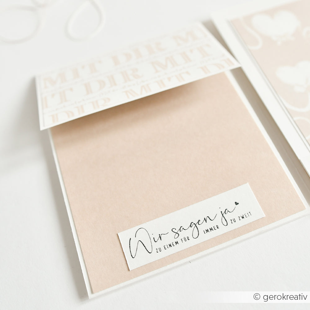 Offene beige-weiße Hochzeitskarte von Alexandra Renke mit deutschem Text "Wir sagen ja" auf der Innenseite, hergestellt mit Papierprojekten und einem Holzstempel, auf weißem Hintergrund.