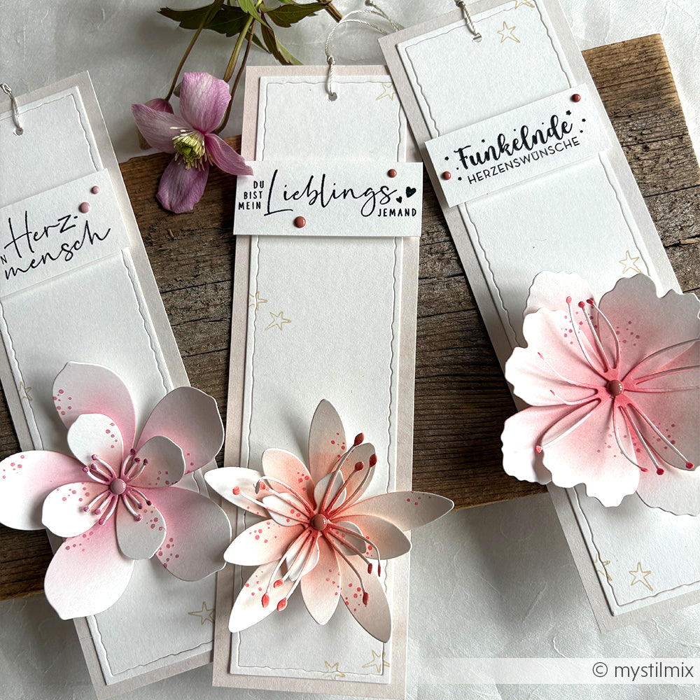 Drei handgefertigte Alexandra Renke-Lesezeichen mit rosa 3D-Blumen und deutschem Text auf einer Holzoberfläche - perfekt für Fans von kreativen Stempelgummi und Holzstempel-Basteleien.