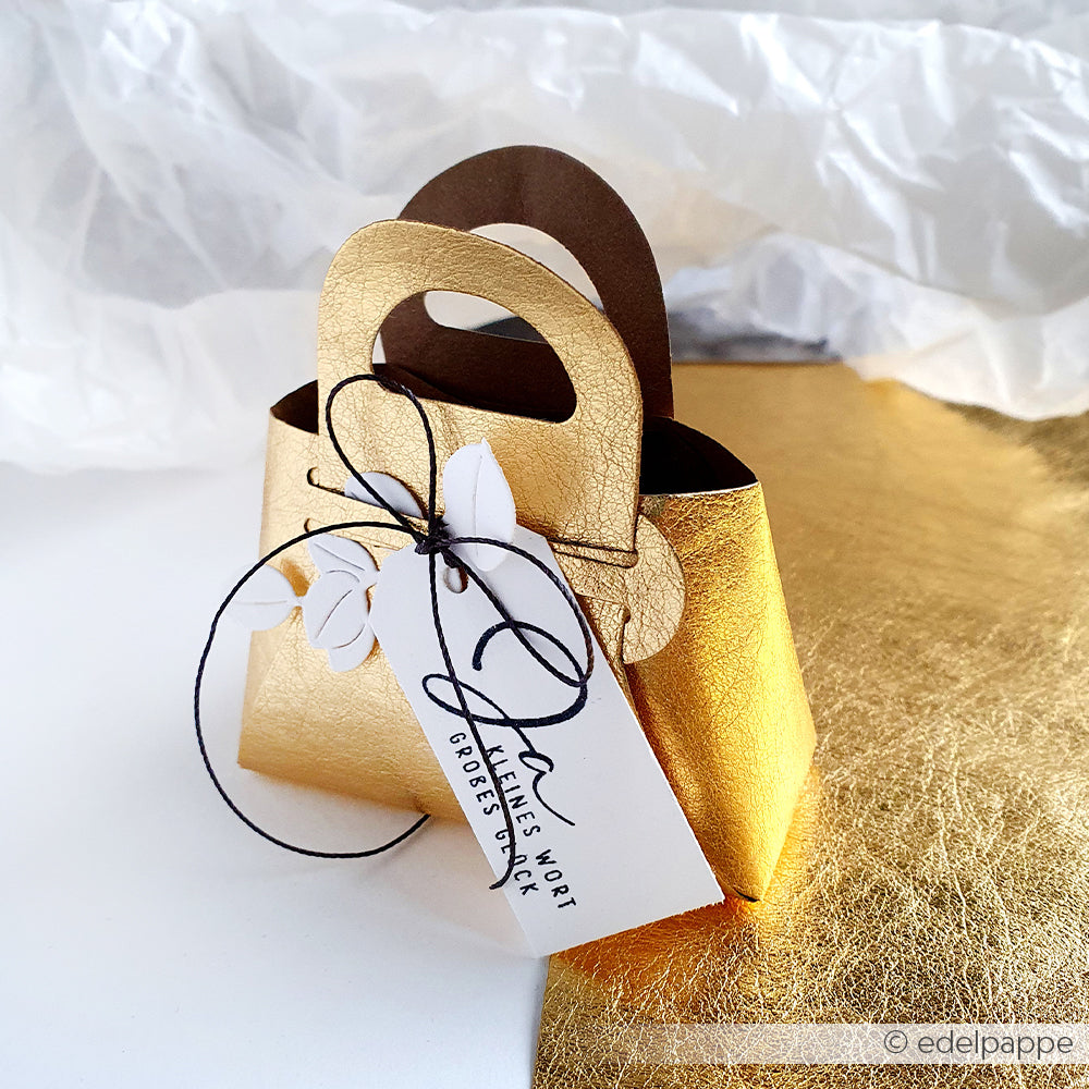 Diese kleine goldene Papiertasche von Alexandra Renke ist mit einem Geschenkanhänger, einer schwarzen Schnur und einer Blattdekoration versehen - perfekt, um sie zusammen mit Ihrem Lieblings-Stempelkissen oder Holzstempel zu verschenken.