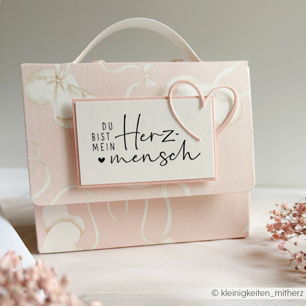 Rosafarbene Geschenkschachtel mit Herzmotiv von Alexandra Renke, mit einem charmanten Holzstempel und einer Karte mit der Aufschrift "Du bist mein Herzmensch" - ideal für Papierprojekte.