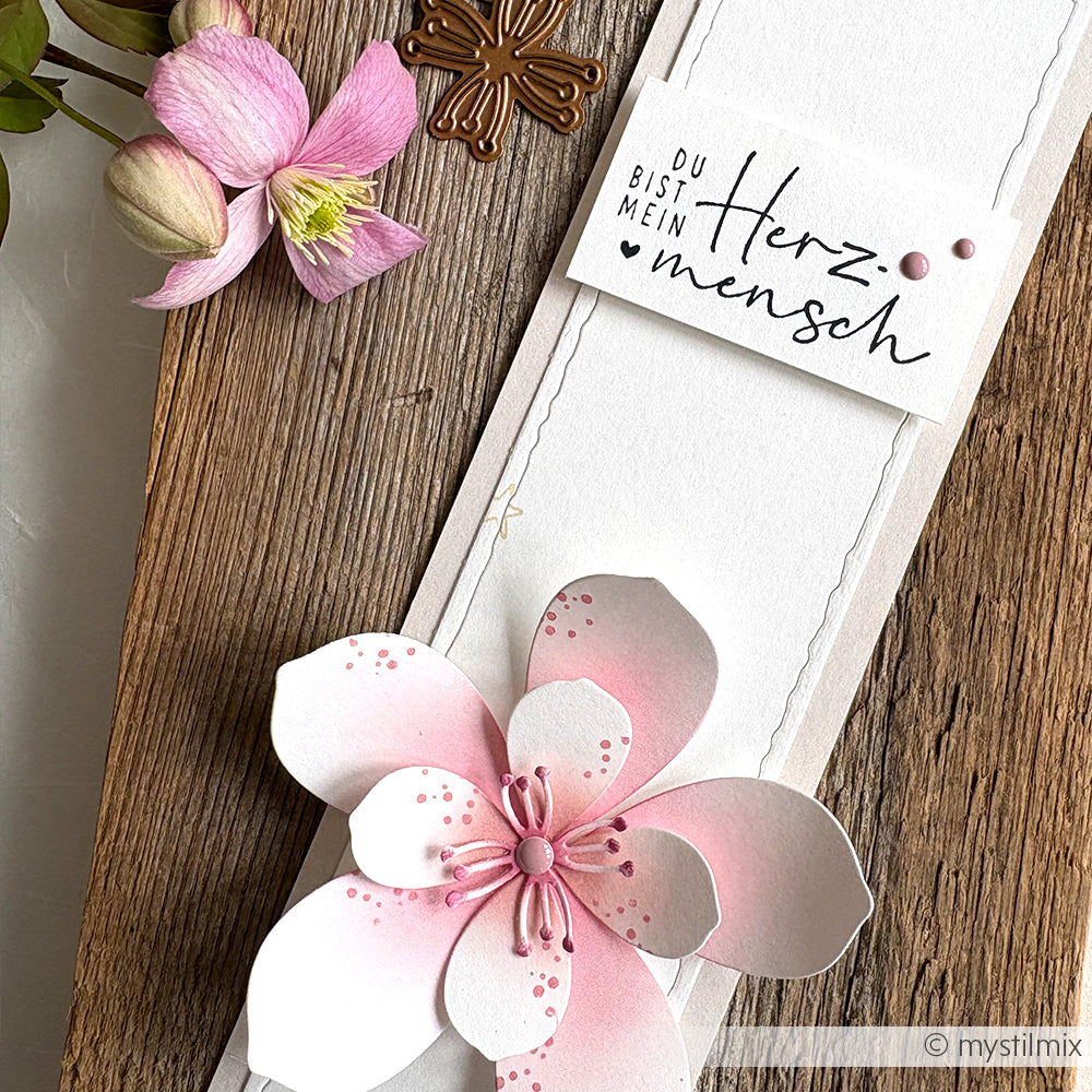 Eine handgefertigte Karte von Alexandra Renke mit rosafarbenen Blumen, einem bronzenen Kreuz und einem "Mein Herzmensch"-Schriftzug, akzentuiert durch zarte Holzstempel-Details und sanfte Stempelkissen-Farben.