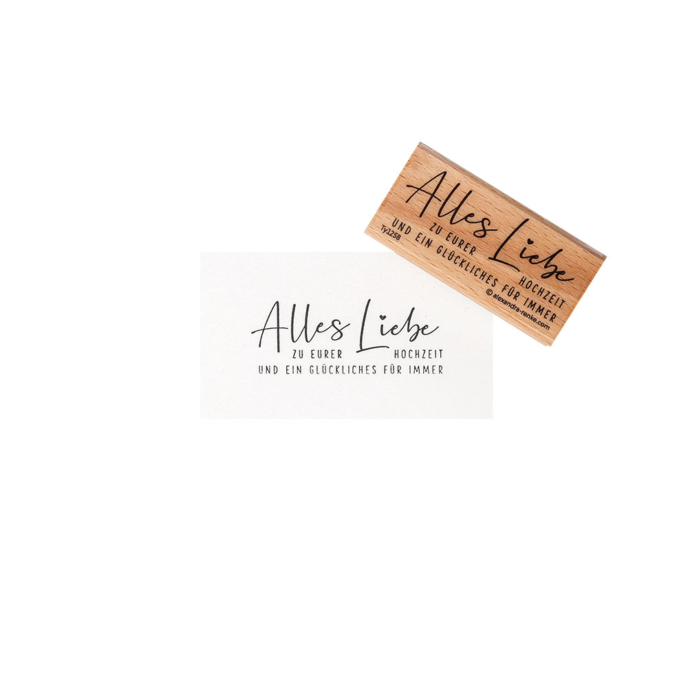Eine weiße Karte und eine Alexandra Renke-Premium-Holzbriefmarke mit dem deutschen Text "Alles Liebe zu eurer Hochzeit und ein glückliches für immer".
