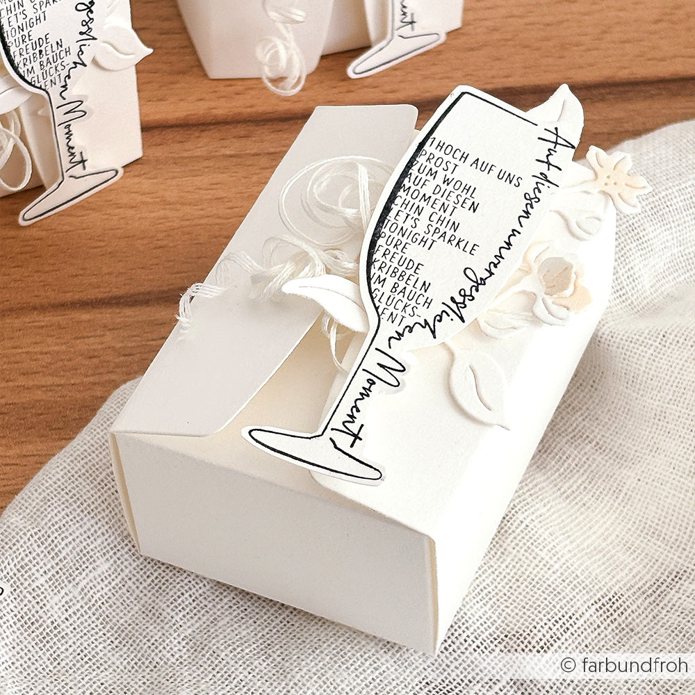 Weiße Geschenkbox von Alexandra Renke mit einem Sektglas aus Papier, handgeschriebener Schrift und weißen Blumenakzenten - ideal für Papierprojekte oder zum Aufwerten Ihrer Lieblings-Stempelgummi-Designs.