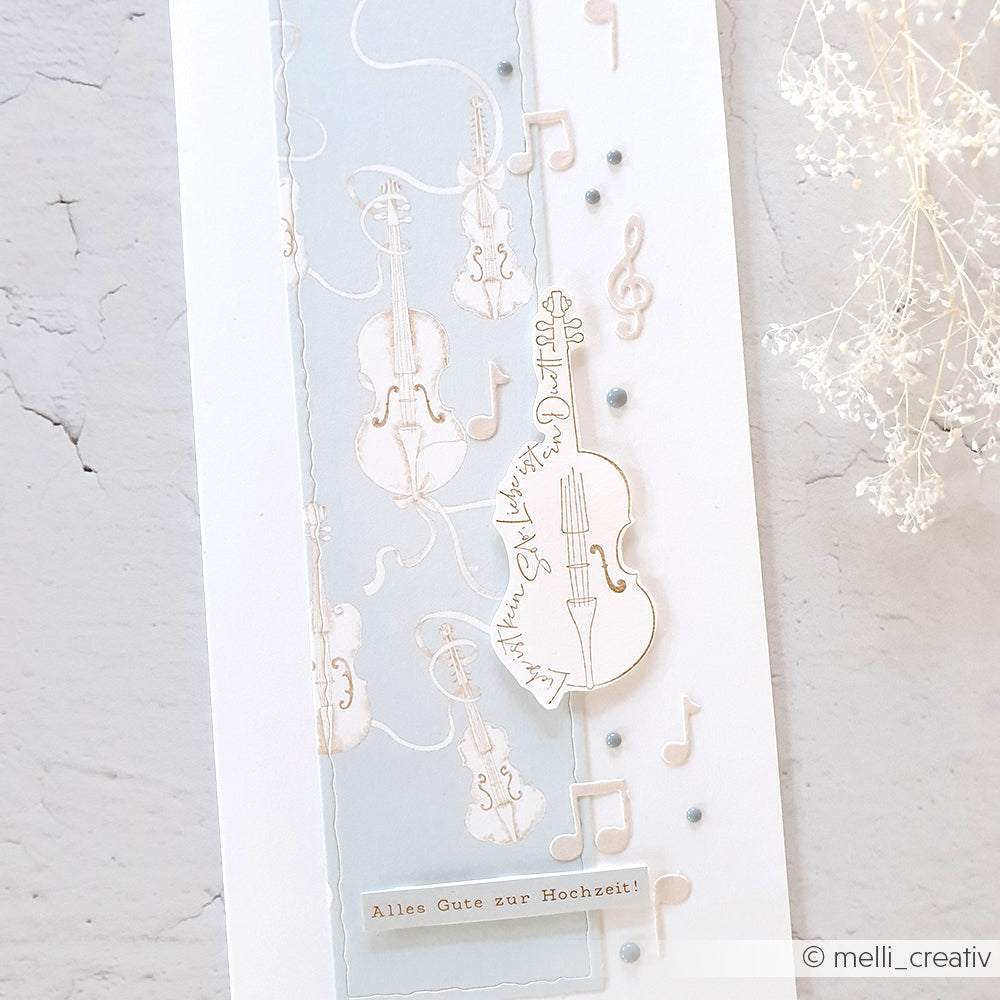 Eine Hochzeitskarte von Alexandra Renke mit Geigen, Musiknoten und "Alles Gute zur Hochzeit!" auf blau-weißem Hintergrund, mit dem herzlichen Spruch "Liebe ist ein Duett" für einen romantischen Touch.