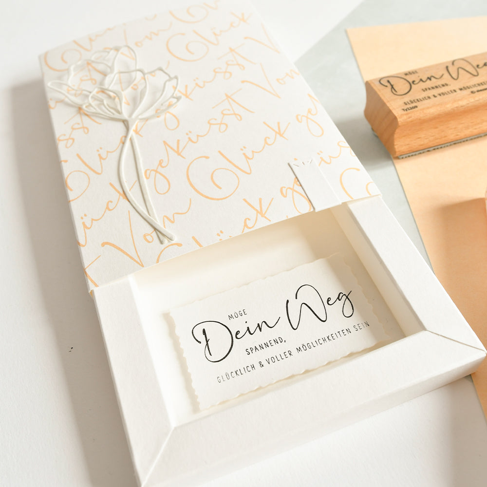 Elegante weiße Alexandra Renke Geschenkbox mit goldener Schreibschrift, floralem Design und einer Karte mit der Aufschrift "Möge Dein Weg" - perfekt für Papierprojekte oder zur individuellen Gestaltung mit Holzstempeln oder Stempelgummi.