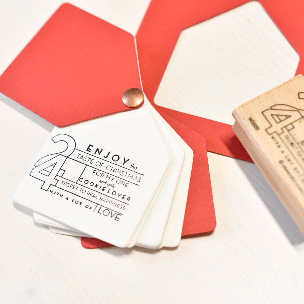 Weiße Geschenkanhänger im Stapel, verziert mit einem Holzstempel mit der Aufschrift Enjoy the taste of Christmas.