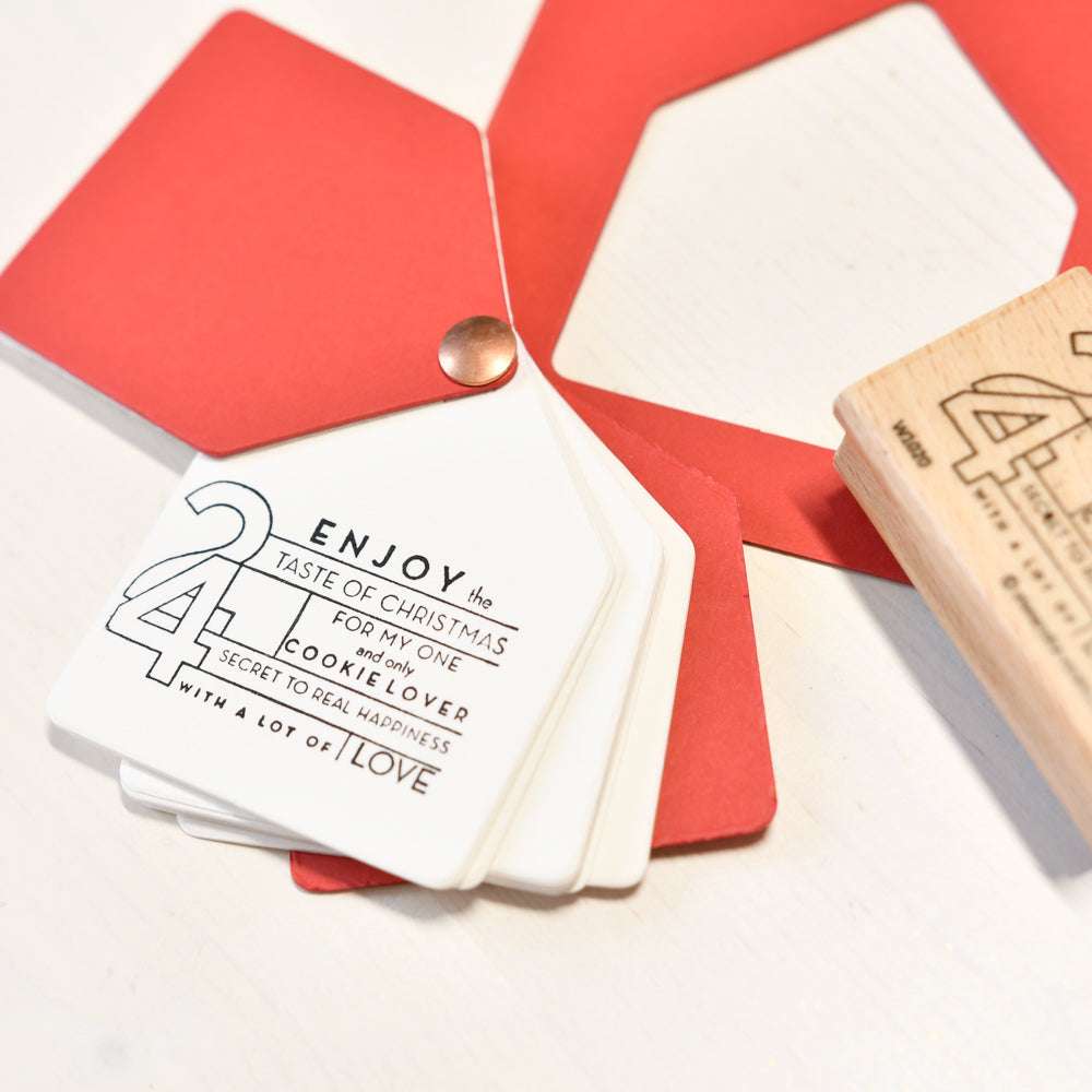 Quadratische Alexandra Renke Karten mit einer festlichen Botschaft über Weihnachten, Plätzchen und Liebe werden neben einem roten Umschlag aufgefächert - perfekt für weihnachtliche Papierprojekte oder in Kombination mit Ihrem Lieblingsholzstempel.