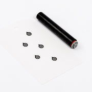 Ein schwarzer Akzentstempel und eine weiße Karte mit fünf blumenförmigen Stempelabdrücken.