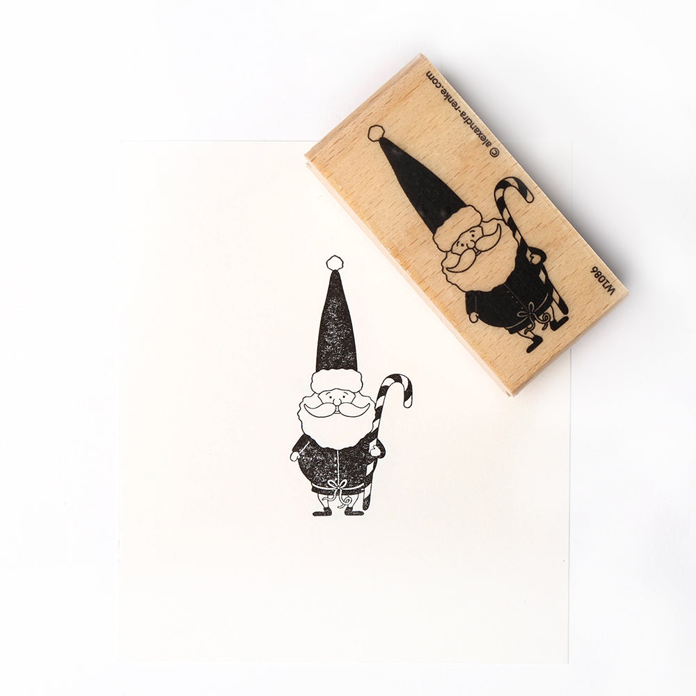 Der Alexandra Renke-Gummistempel und sein schwarzer Tintenaufdruck eines lächelnden Weihnachtsmanns mit einer Zuckerstange verleihen jedem Papierprojekt auf weißem Papier einen festlichen Charme.