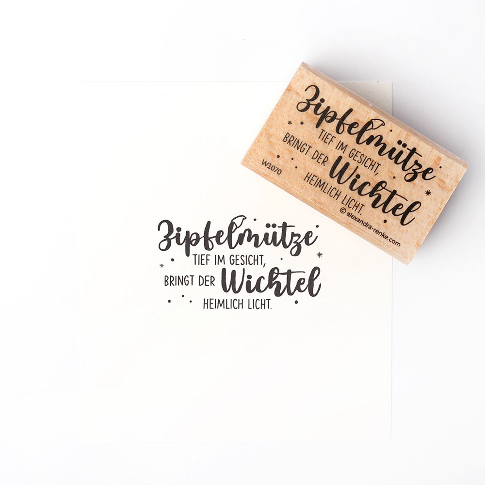 Ein Holzstempel von Alexandra Renke mit deutschem Text und dekorativen Sternen, gefertigt aus hochwertigem Holz, gezeigt mit seinem Druck auf weißem Hintergrund.