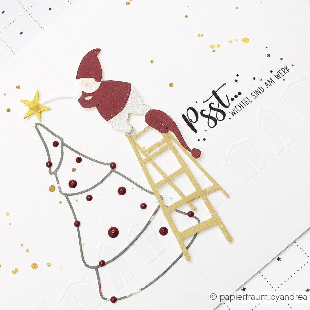 Ein Alexandra Renke Holzstempel zeigt einen Wichtel auf einer Leiter, der einen Stern auf einen minimalistischen Weihnachtsbaum mit dem Text "Pst... Wichtel sind am Werk"-Ideal für festliche Papierprojekte und kreative Weihnachtsgestaltung.