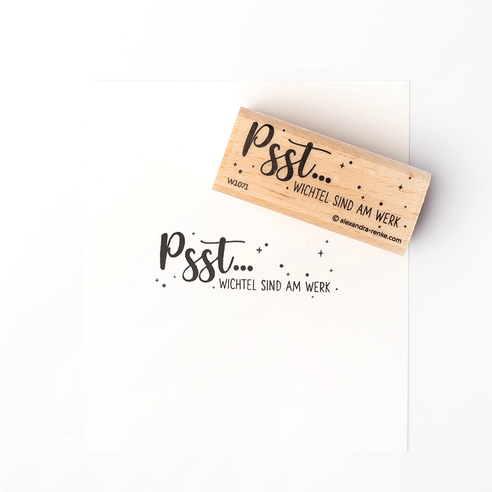 Der Alexandra Renke Holzstempel und sein "Psst... Wichtel sind am Werk." auf weißem Papier ist ideal für kreative Papierprojekte mit Stempeln.