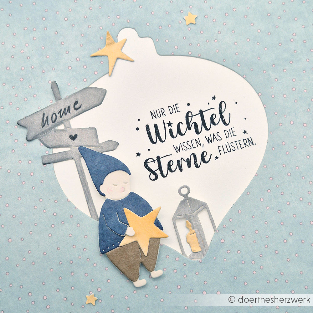 Ein Gnom hält einen Stern an einer Laterne und ein Hausschild; deutscher Text über Elfen und Sterne bildet den Hintergrund. Perfekt für charmante Stempelmotive oder einzigartige Holzstempel mit hochwertigem Holz von Alexandra Renke.