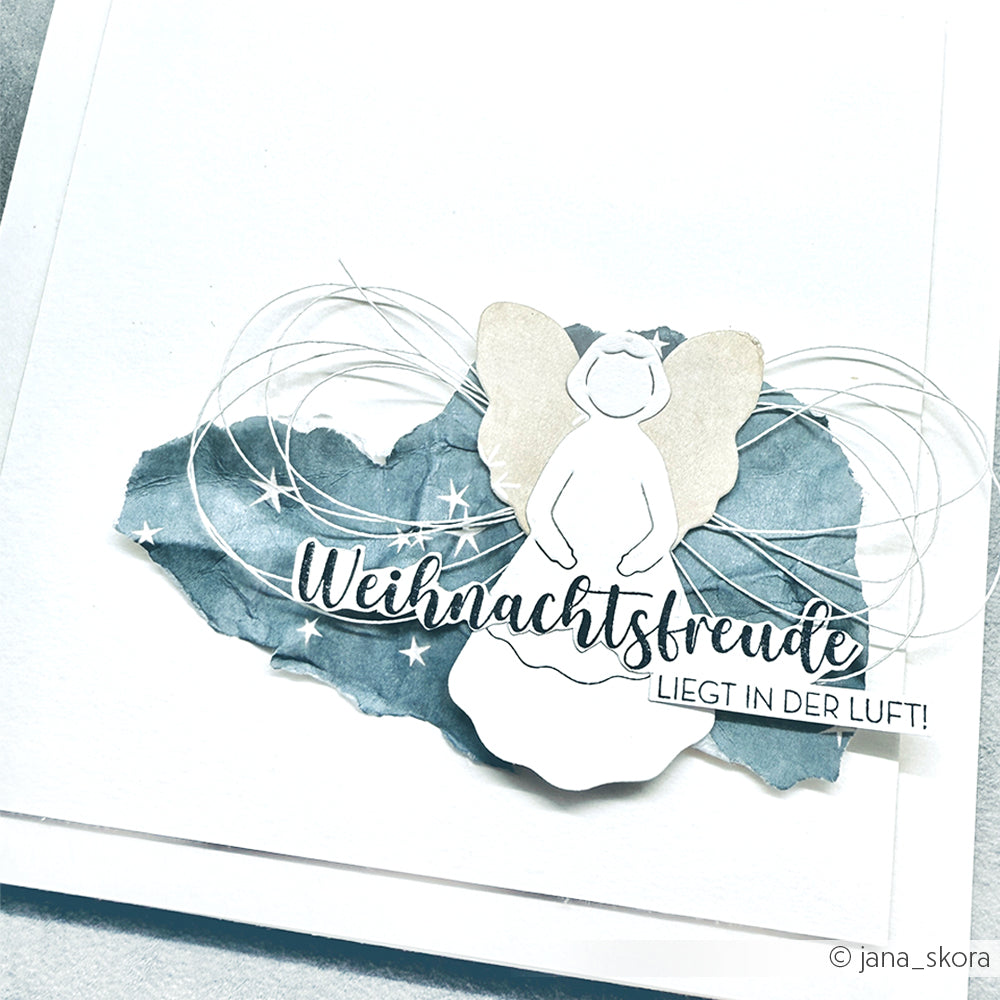 Handgemachte Weihnachtskarte von Alexandra Renke mit einem Engel auf blauem Hintergrund und dem Text "Weihnachtsfreude liegt in der Luft!" Gestempelt für eine einzigartige Note.