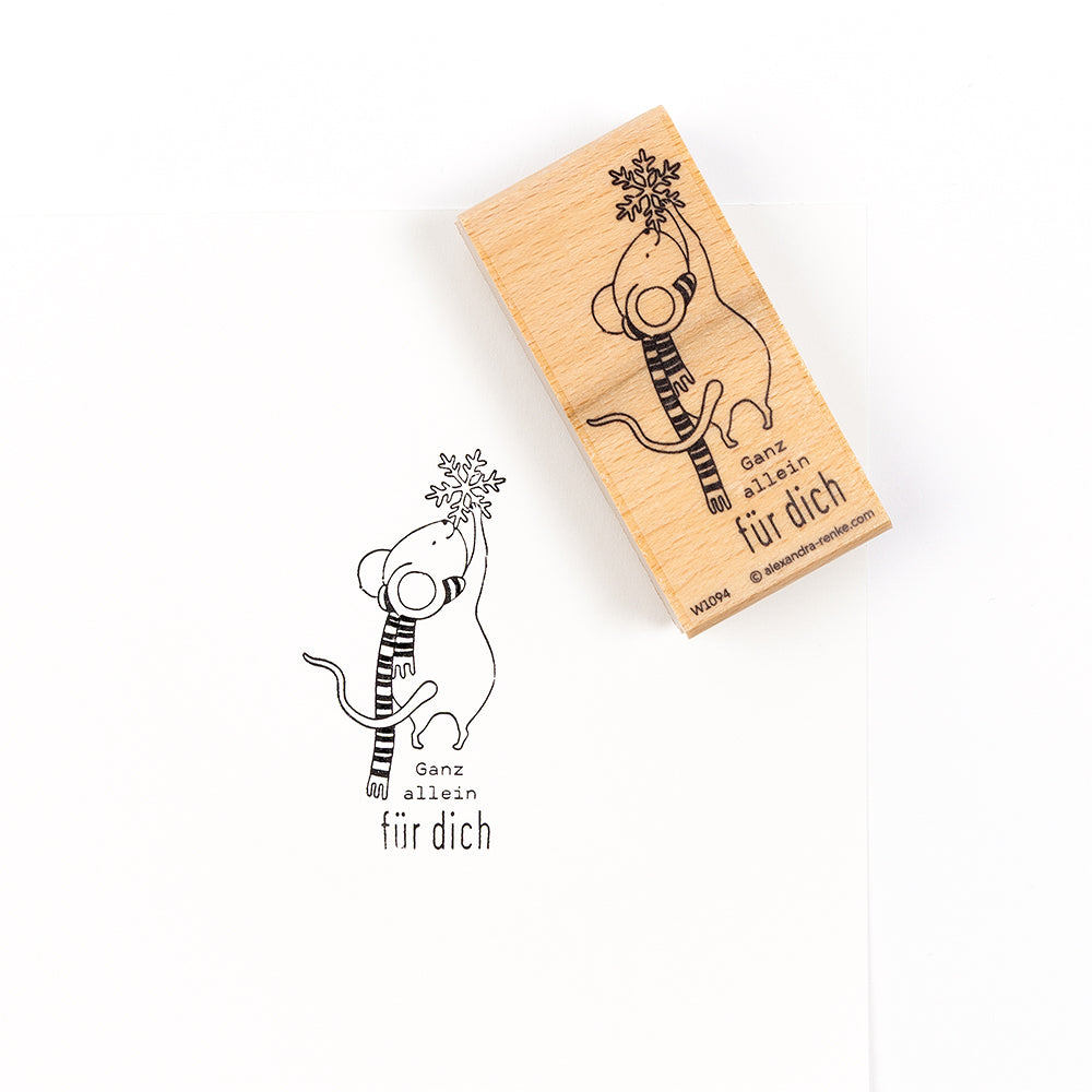 Ein Holzstempel, der eine Maus mit einem Schal zeigt, die eine Schneeflocke hält, neben dem Stempelabdruck auf einem Papierprojekt mit der Aufschrift „Ganz allein für dich“.