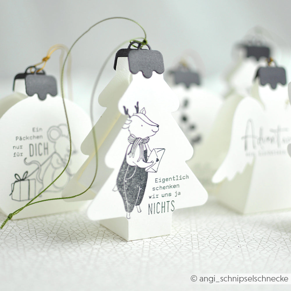 Weihnachtsbaumschmuck aus Papier mit Stempelmotiven von illustrierten Tieren und deutschem Text.