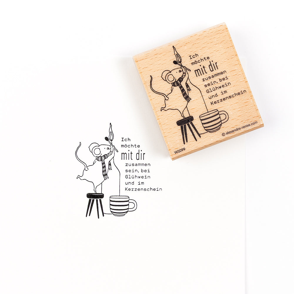 Ein Holzstempel mit der Abbildung einer Maus mit Schal, die auf einem Hocker neben dem deutschen Text „Ich möchte mit dir zusammen sein, bei Glühwein und im Kerzenschein“ steht.