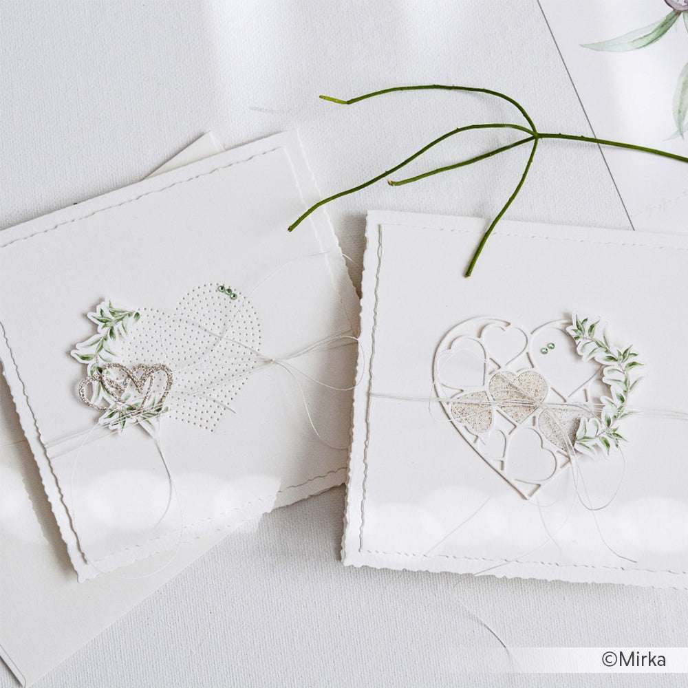 Zwei elegante, handgefertigte weiße Karten mit Herz- und Blattmotiven aus hochwertigem Alexandra Renke-Papier werden auf einer weißen Oberfläche präsentiert.