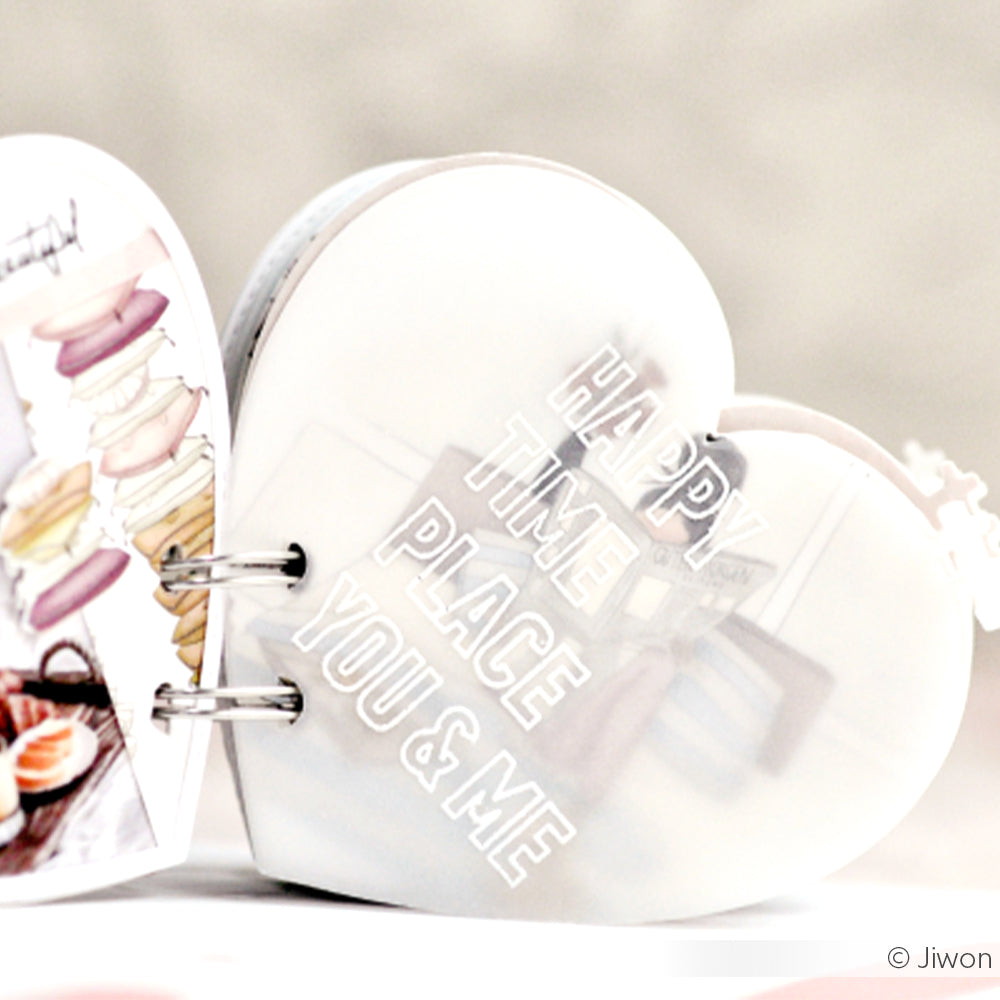 Ein herzförmiges Büchlein von Alexandra Renke mit Designpapier und dem Schriftzug "HAPPY TIME PLACE YOU & ME" in weißen Großbuchstaben auf dem Umschlag.