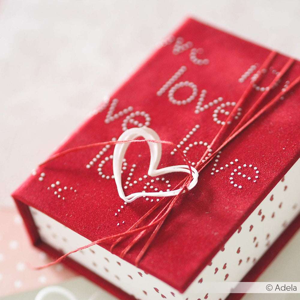Rote Geschenkschachtel mit dem Schriftzug "love", verschnürt mit roter Schnur und einem weißen Herz - ideal zum Kombinieren mit Dies, um mit Ihren Lieblingsdesignpapieren einzigartige, persönliche Akzente zu setzen. Marke: Alexandra Renke.