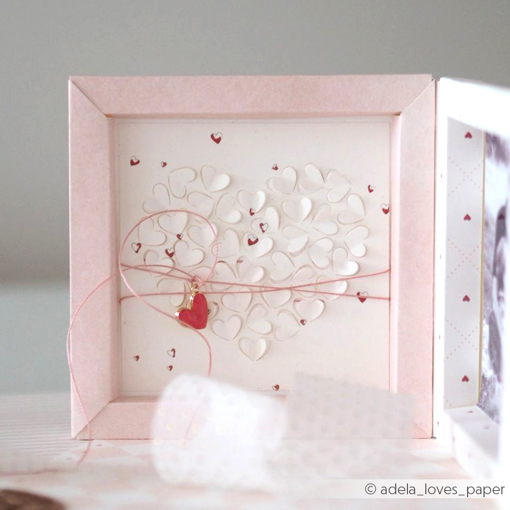 Eine handgefertigte Karte von Alexandra Renke mit weißen 3D-Herzen in Herzform, gefertigt mit Motivstanze Herz, rosa Kordel und einem kleinen roten Herzanhänger.