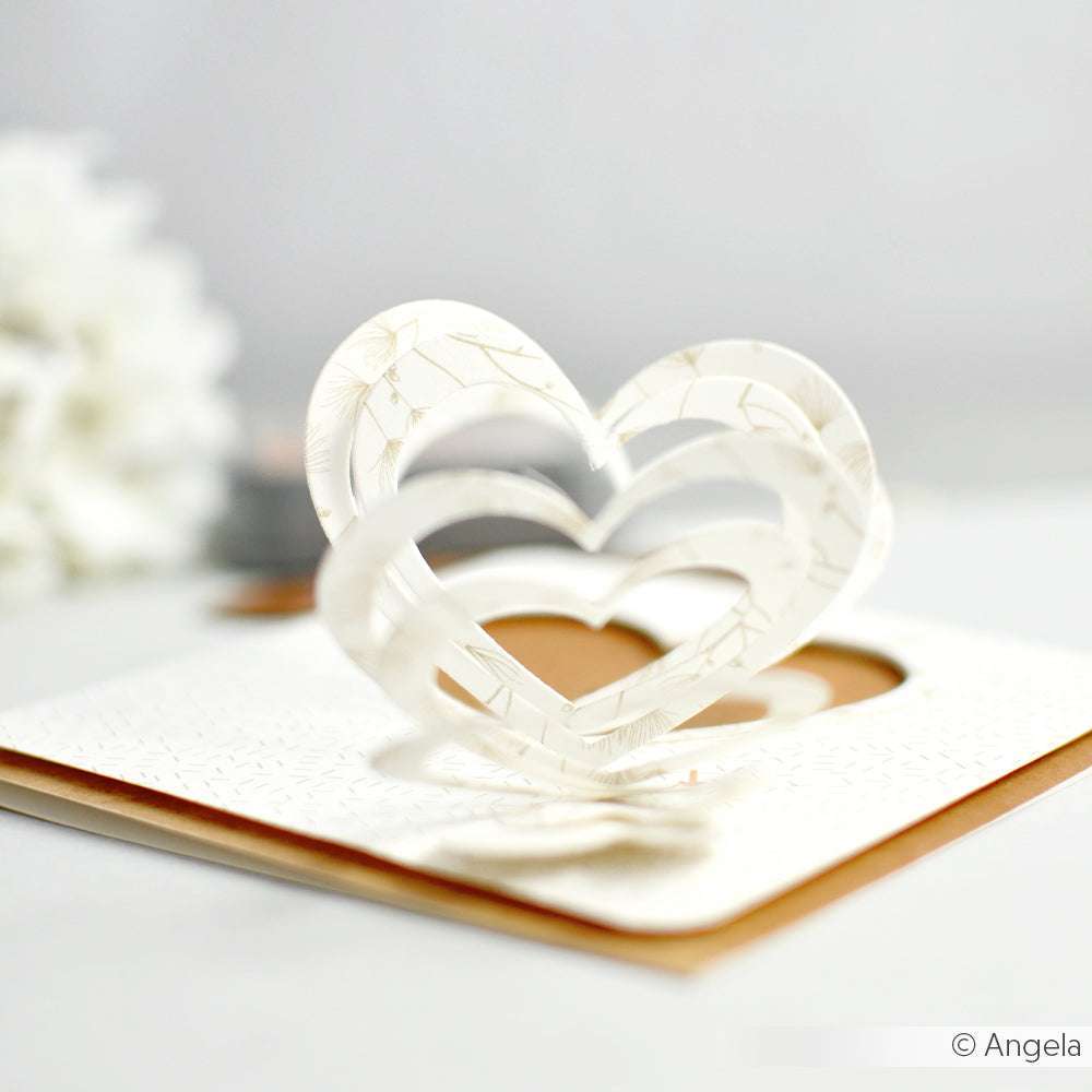 Pop-up-Grußkarte mit geschichteten weißen Herzformen, gestaltet mit der Alexandra Renke Motivstanze Herzspirale, die offen auf einem strukturierten weißen Hintergrund dargestellt wird.