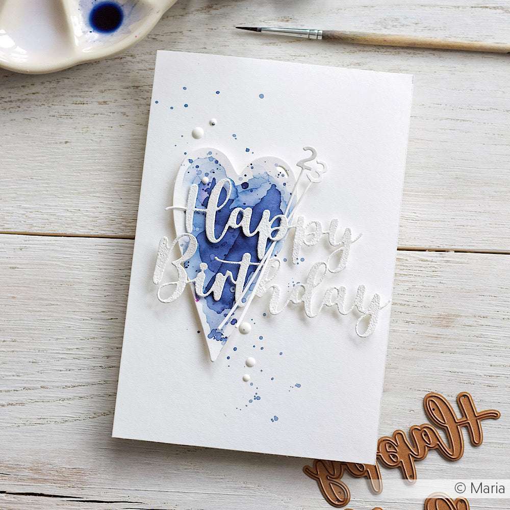 Handgefertigte Karte von Alexandra Renke mit einem blauen Aquarellherz, das mit Designpapieren und Motivstanze Herz-Tag Dies hergestellt wurde, sowie dem Text "Happy Birthday" neben einem Pinsel und einer Palette.