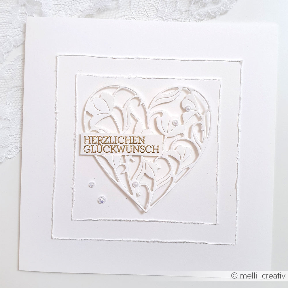 Weiße Karte mit einem verschlungenen Herzmotiv aus der Motivstanze Blumenherz von Alexandra Renke und einem eleganten goldenen Schriftzug "Herzlichen Glückwunsch" in der Mitte.