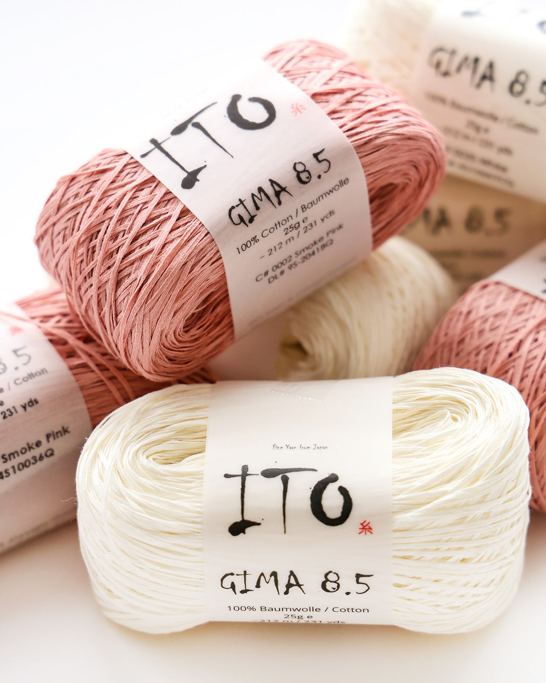 Mehrere Stränge des Baumwollgarns ITO Gima 8.5 in Rosa und Weiß, gestapelt auf einer weißen Fläche.