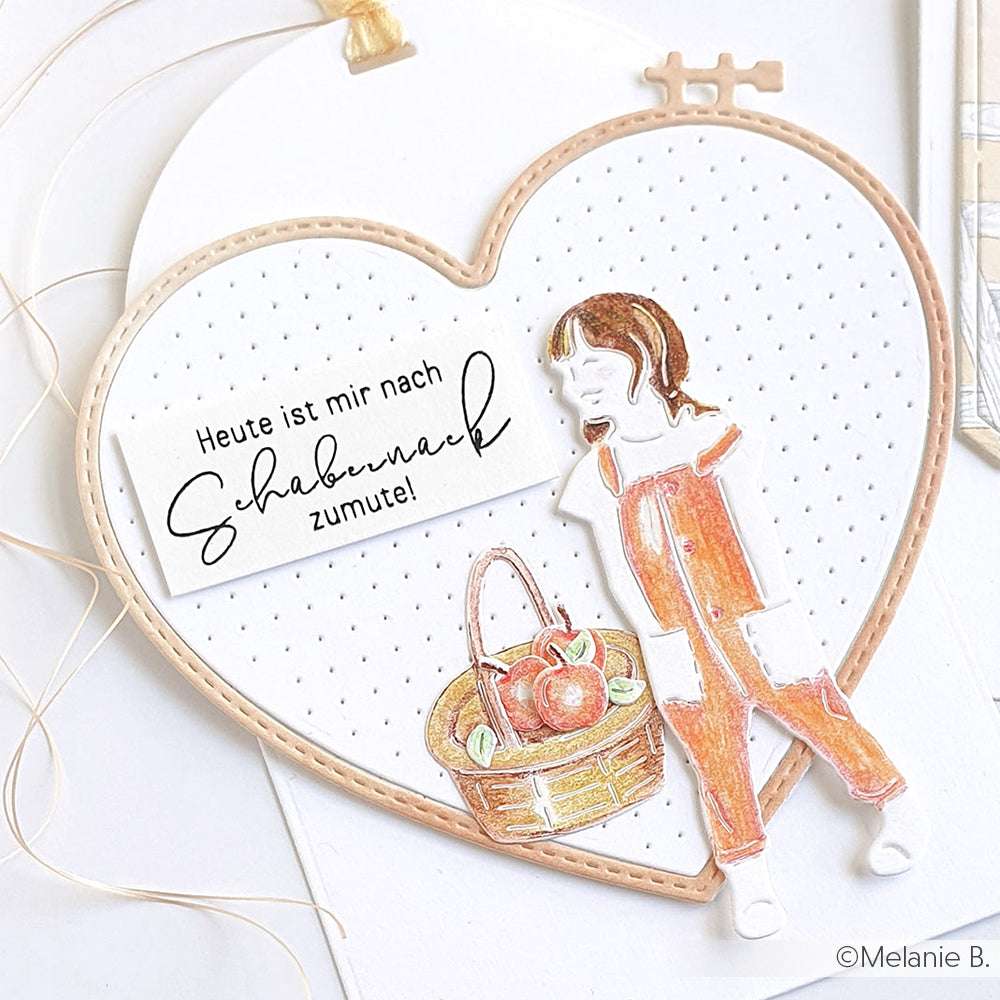 Herzförmige Karte von Alexandra Renke mit deutschem Text und einem Mädchen in orangefarbener Latzhose mit einem Apfelkorb, hergestellt mit DieCut Systemen und Stanzen für präzise Details.