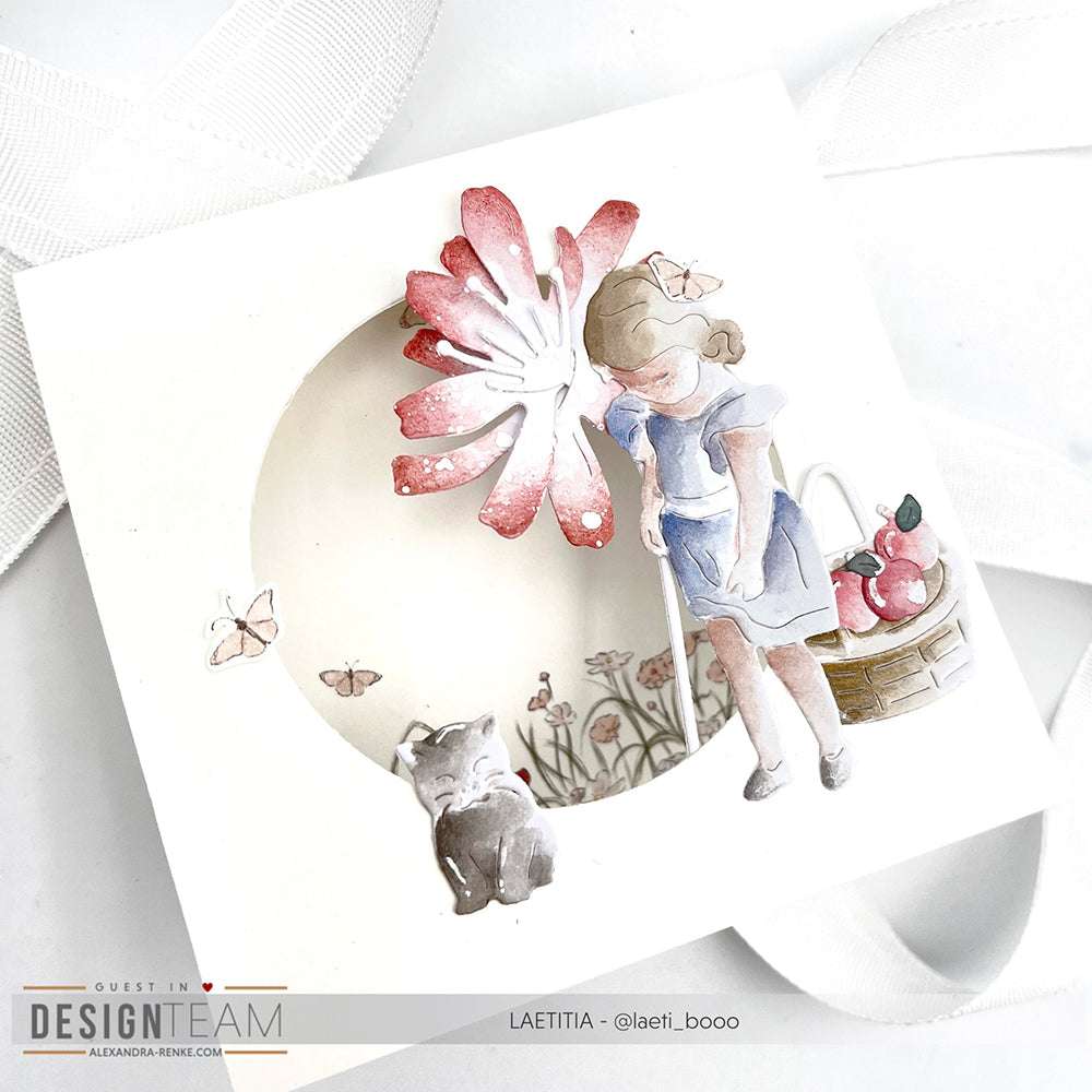 Ein Mädchen in einem blauen Kleid steht neben einer Katze mit Schmetterlingen, Äpfeln und einer rosa Blume - ideal zum Basteln mit der Motivstanze Apfelmädchen von Alexandra Renke oder anderen Dies für Basteln.